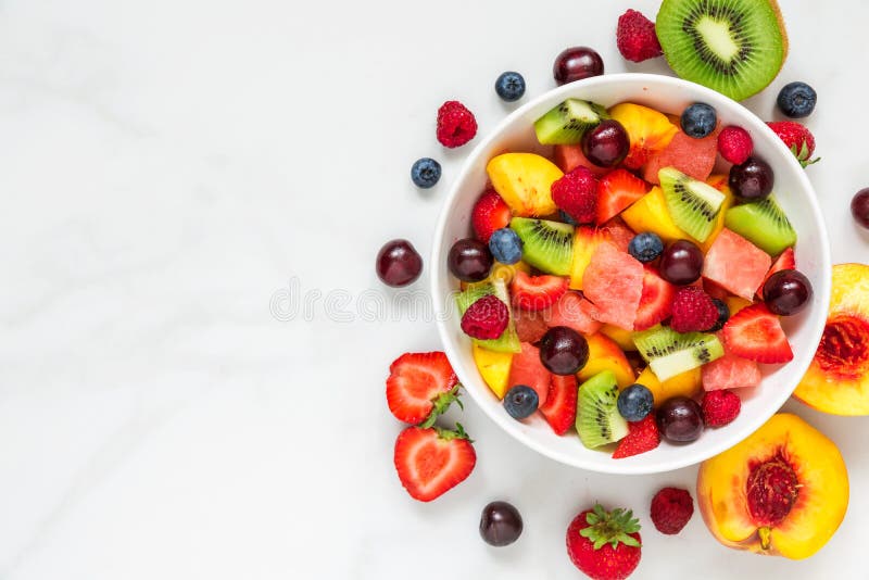 Bowl of healthy fresh fruit salad on white marble background. healthy food. top view