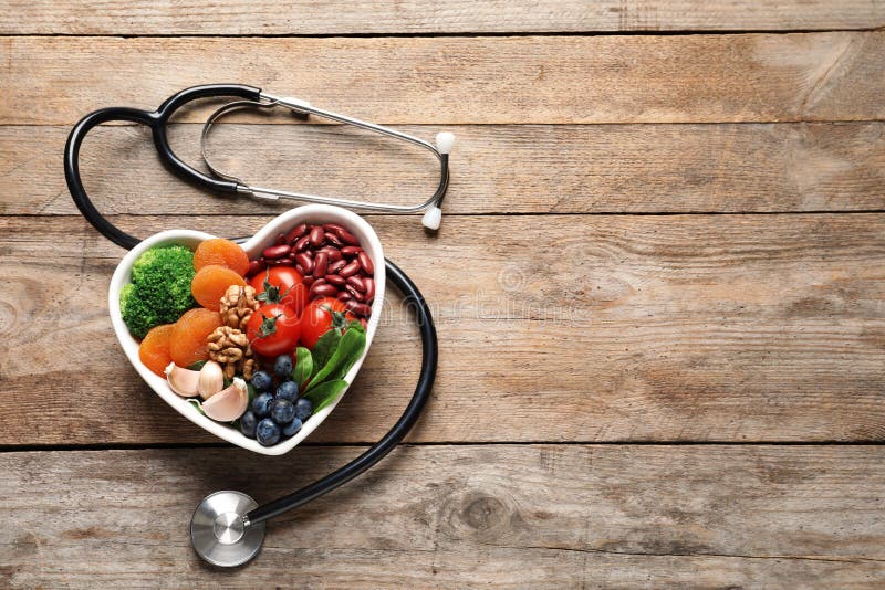 Bowl with heart-healthy diet products and stethoscope on wooden background, top view