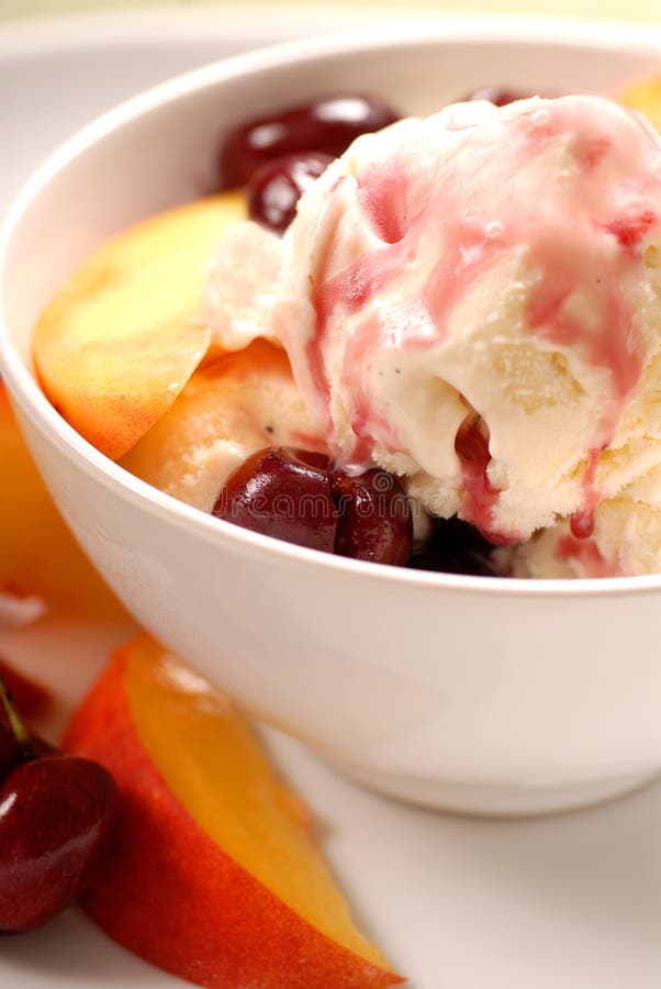 A bowl of ice cream with peaches and cherries