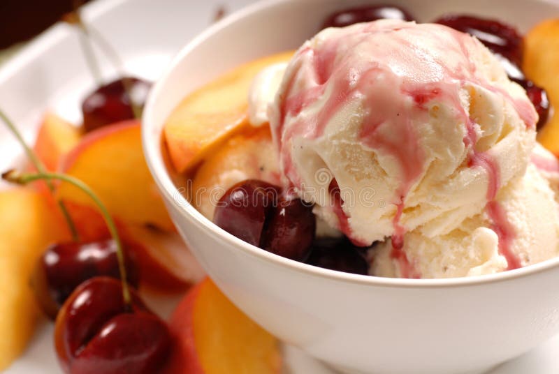 A bowl of ice cream with cherries and peaches