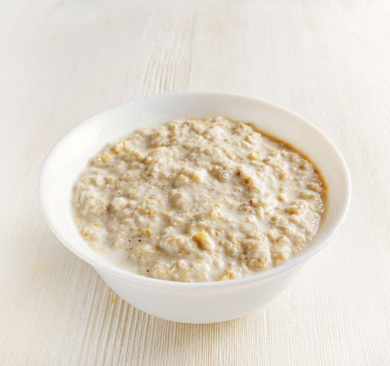 Bowl of oat porridge on wooden table stock photos
