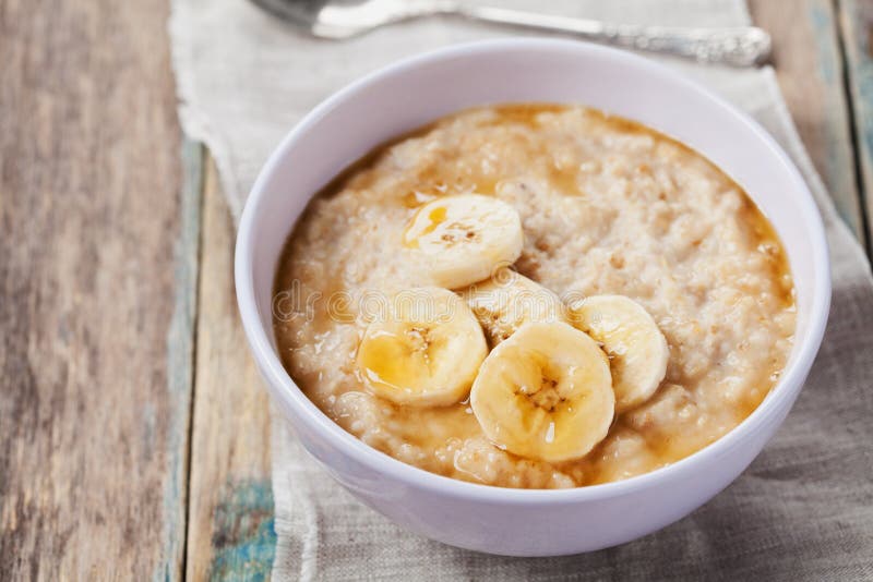 Bowl of oatmeal porridge with banana and caramel sauce on rustic table, hot and healthy breakfast stock image Bowl of oatmeal porridge with banana and caramel sauce on rustic table, hot and healthy breakfast stock image