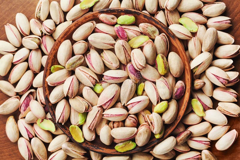 Bowl of pistachio nuts on wooden table top view. Healthy food and snack.