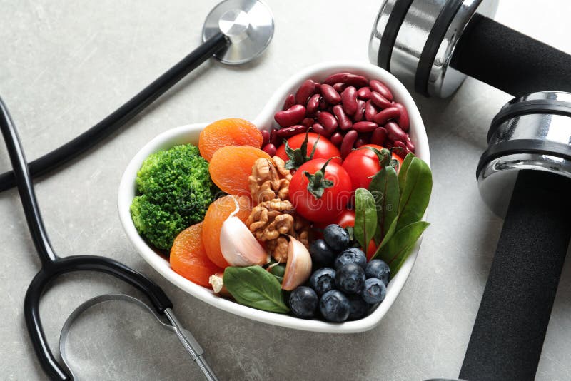 Bowl of products for heart-healthy diet, dumbbells and stethoscope