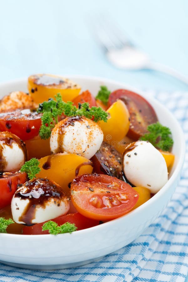 Bowl of salad with mozzarella, balsamic sauce, colorful cherries
