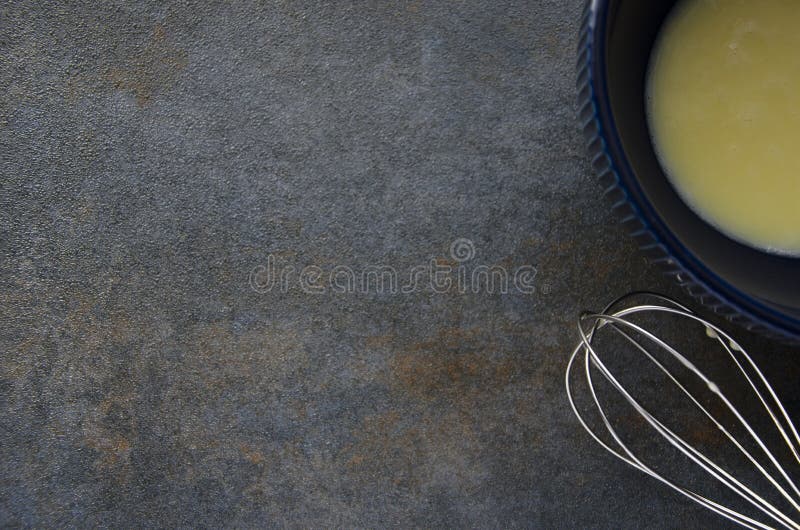 Bowl with scrambled eggs and whisk on grey table.Preparing of fresh omelette