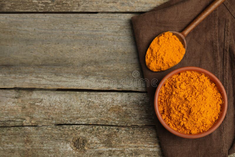 Bowl and spoon with saffron powder on wooden table, top view. Space for text stock photos