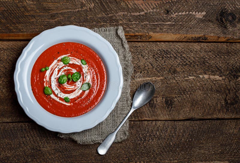 Bowl of Tomato Soup with a Basil on Wooden Background Stock Photo