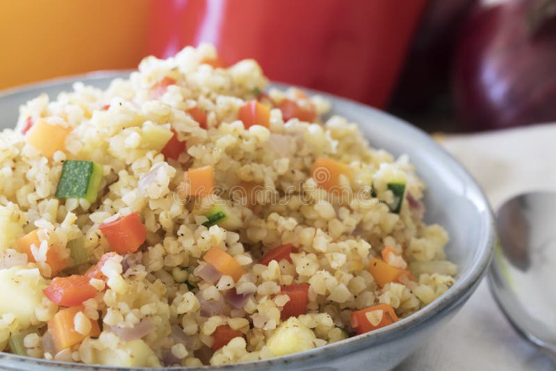 Bowl of vegan bulgur pilaf with carrots, red peppers, onions and zucchini. Bowl of vegan bulgur pilaf with carrots, red peppers, onions and zucchini.