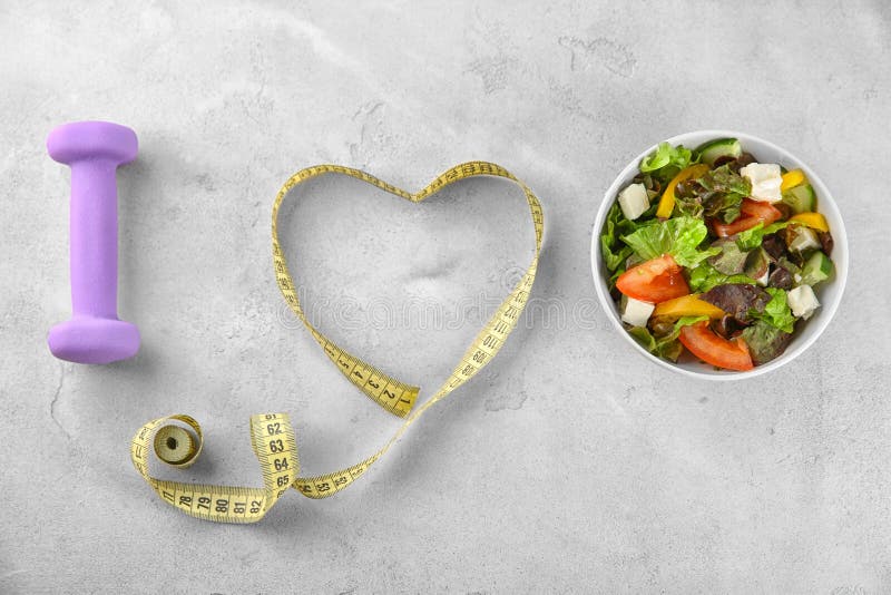 Bowl with vegetable salad, dumbbell and measuring tape on table. I love diet food royalty free stock photos Bowl with vegetable salad, dumbbell and measuring tape on table. I love diet food royalty free stock photos