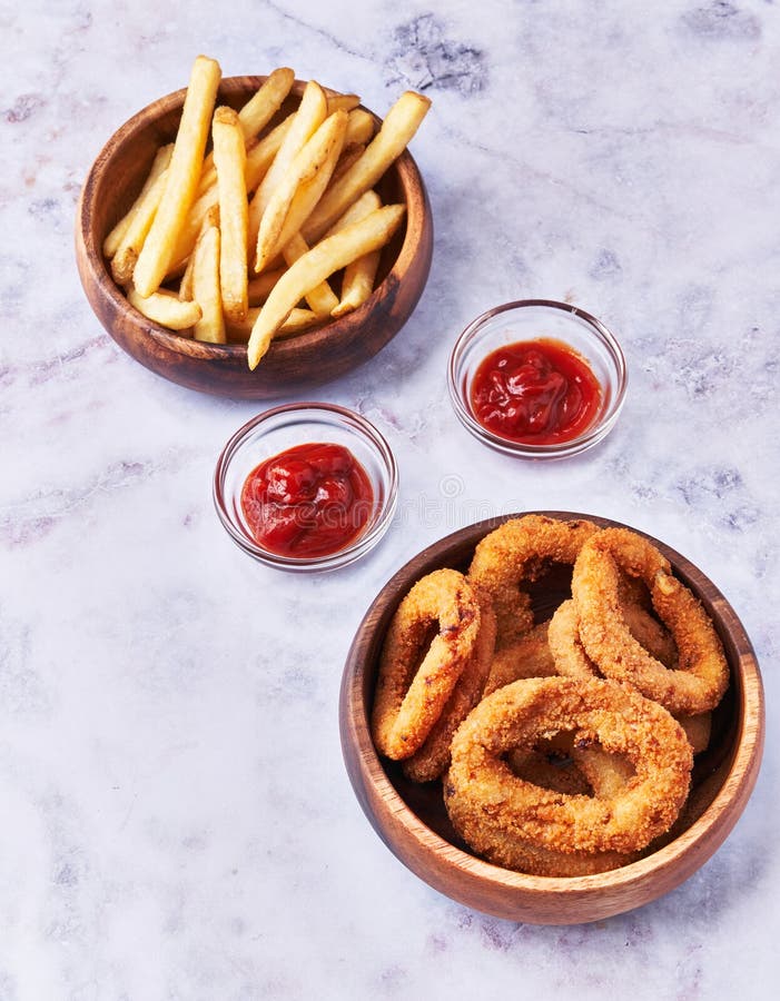 Bowls of Breaded Onion Rings and Potato Chips on a Marble Surface Stock