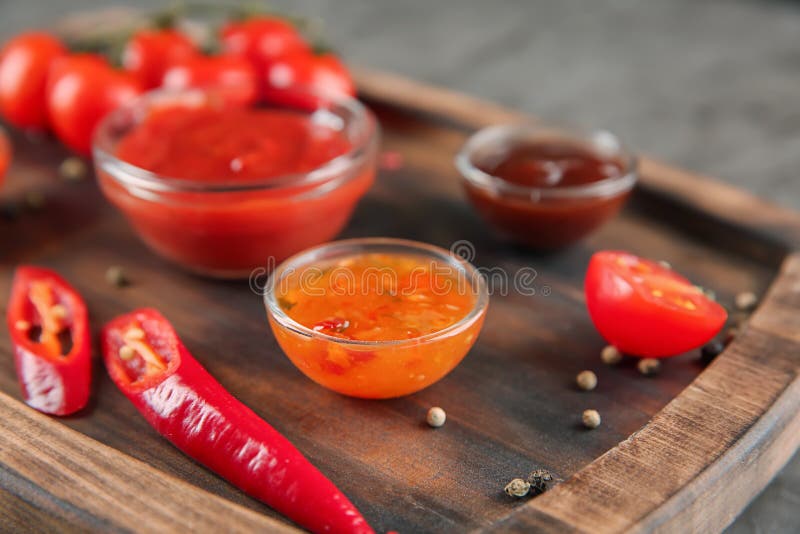 Bowls with Different Red Sauces on Wooden Plate, Closeup Stock Image