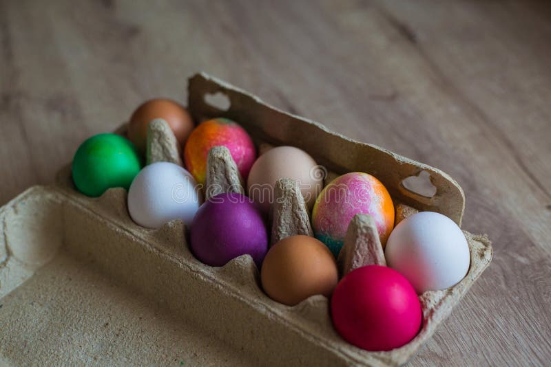 A Box with Multicolored Painted Easter Eggs Stands on a Wooden Table