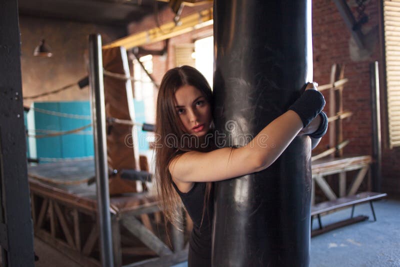 Boxe de combattant de fille avec le sac de sable, trains d'une jeune femme dans le gymnase photos stock Boxe de combattant de fille avec le sac de sable, trains d'une jeune femme dans le gymnase photos stock