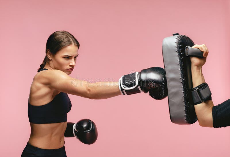 Boxeador de sexo femenino en guantes que entrena con los cojines del boxeo imagenes de archivo Boxeador de sexo femenino en guantes que entrena con los cojines del boxeo imagenes de archivo