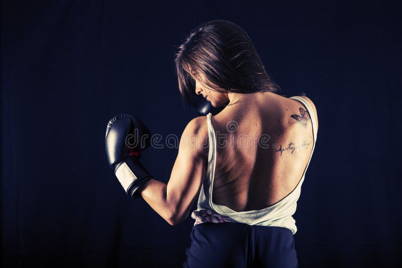 Boxeo fuerte de la mujer joven que realiza un retroceso del gancho foto de archivo libre de regalías Boxeo fuerte de la mujer joven que realiza un retroceso del gancho foto de archivo libre de regalías