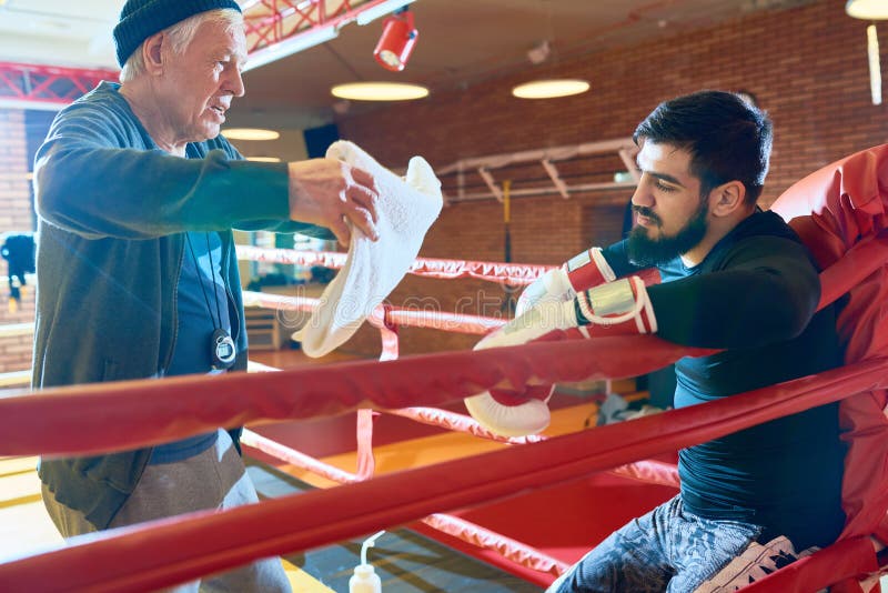 Boxer, der Pause auf Ring mit Trainer macht lizenzfreies stockbild Boxer, der Pause auf Ring mit Trainer macht lizenzfreies stockbild
