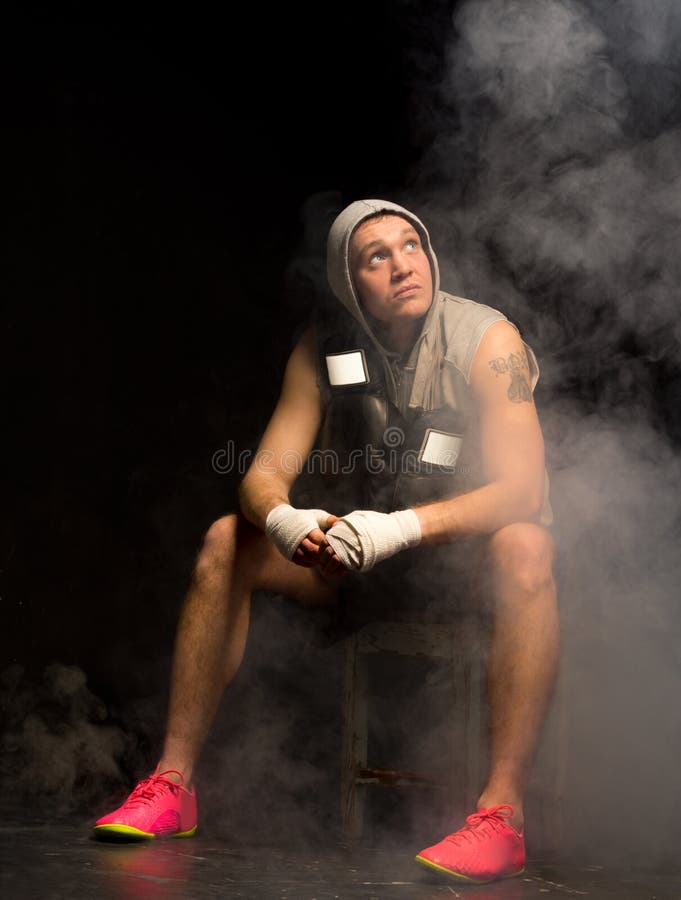 Boxer psyching himself before a fight sitting on a stool in a smoky atmosphere looking up into the air as though seeking help from heaven