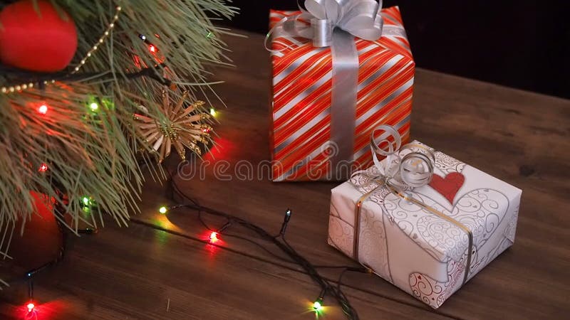 Boxes of gifts are under the tree. Gifts are Packed in colorful paper and tied with string and ribbons. Christmas