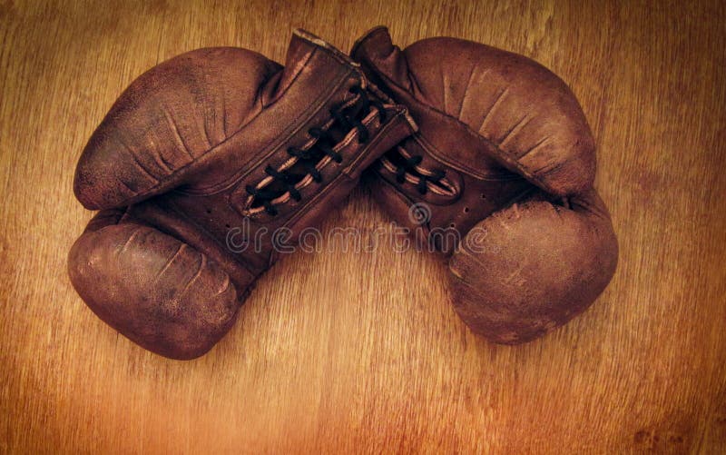 Boxing gloves. Old vintage retro pair of leather worn mittens are on the wood table. Red colors and soft lights