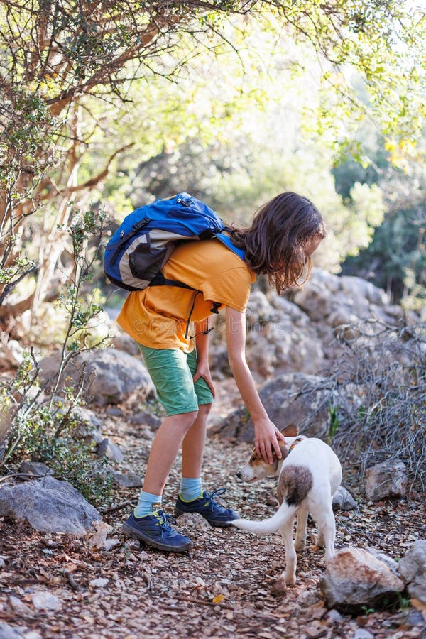A Boy With A Backpack Walks Along A Mountain Path With A Dog Trekking With An Animal And A A Boy With A Backpack Walks Along A Mountain Path With A Dog Trekking With An Animal And A