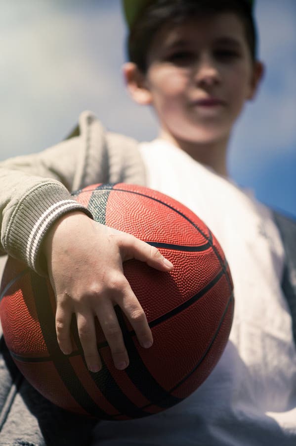 A Boy with a Basketball Ball on the Background of the Sky . the Concept
