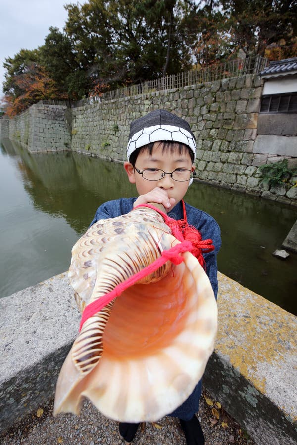 Boy is blowing a snail-trumpet