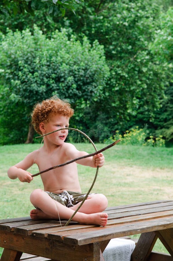 Boy with Bow and Arrow. Little boy (4) on a hot summer day, sitting on a table, playing indian with a handmade bow and arrow stock photography Boy with Bow and Arrow. Little boy (4) on a hot summer day, sitting on a table, playing indian with a handmade bow and arrow stock photography