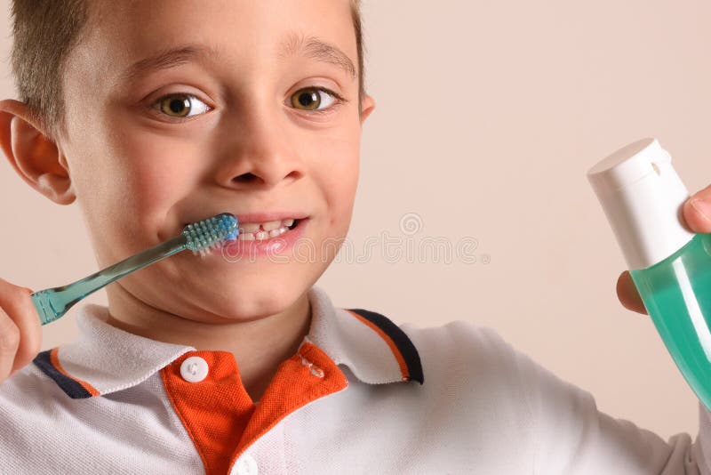 Boy brushing teeth with toothbrush on isolated brown stock photo Boy brushing teeth with toothbrush on isolated brown stock photo
