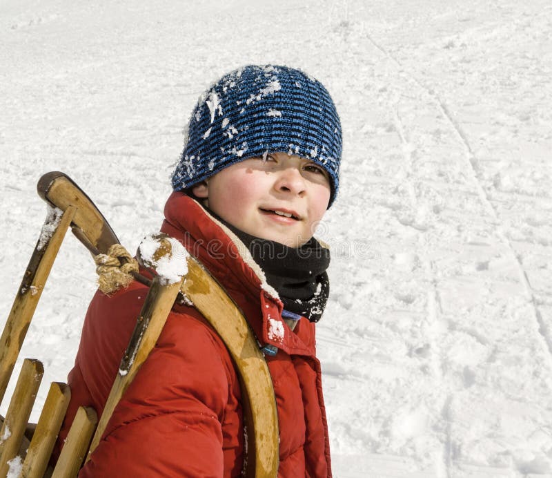 Boy carries his sledge up the hill