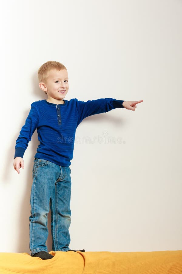 Boy child kid preschooler standing on back rest of sofa interior