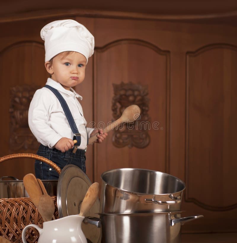 Boy in a cook cap among pans and vegetables