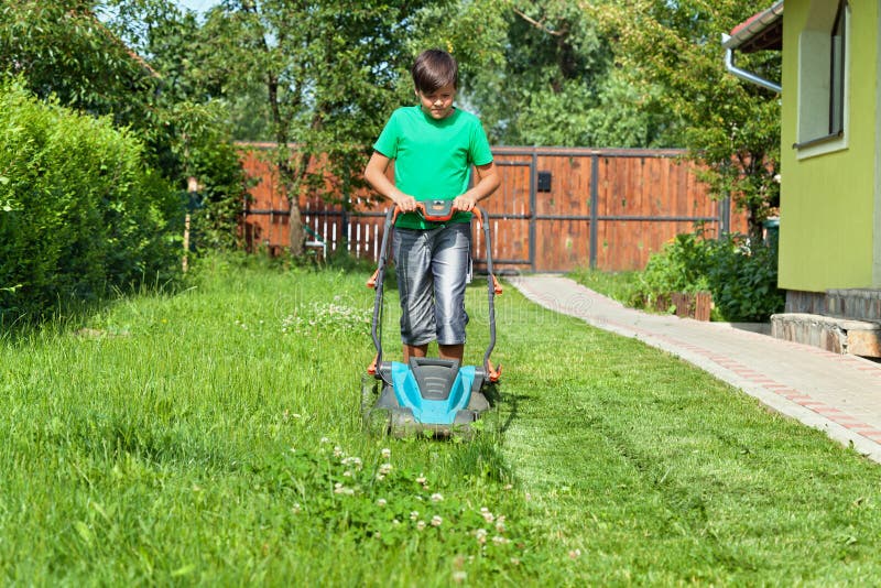Boy cutting grass around the house in summertime royalty free stock photo Boy cutting grass around the house in summertime royalty free stock photo