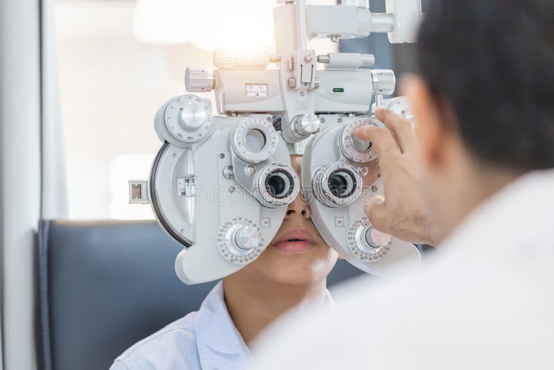 Boy doing eye test checking examination with optometrist in optical shop, Optometrist doing sight testing for child patient in