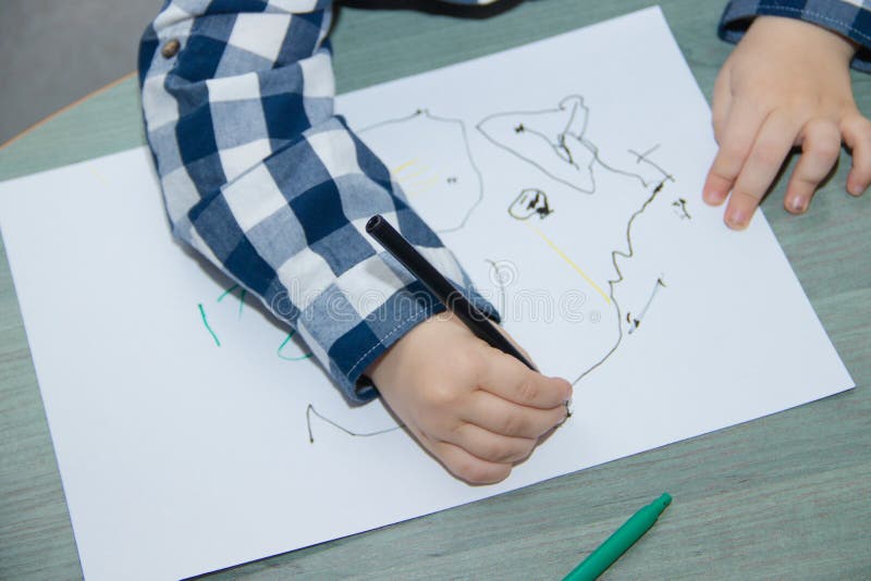 The boy draws felt-tip pens on paper. Drawing. Little boy. Children`s drawing. Developmental activities royalty free stock photo The boy draws felt-tip pens on paper. Drawing. Little boy. Children`s drawing. Developmental activities royalty free stock photo