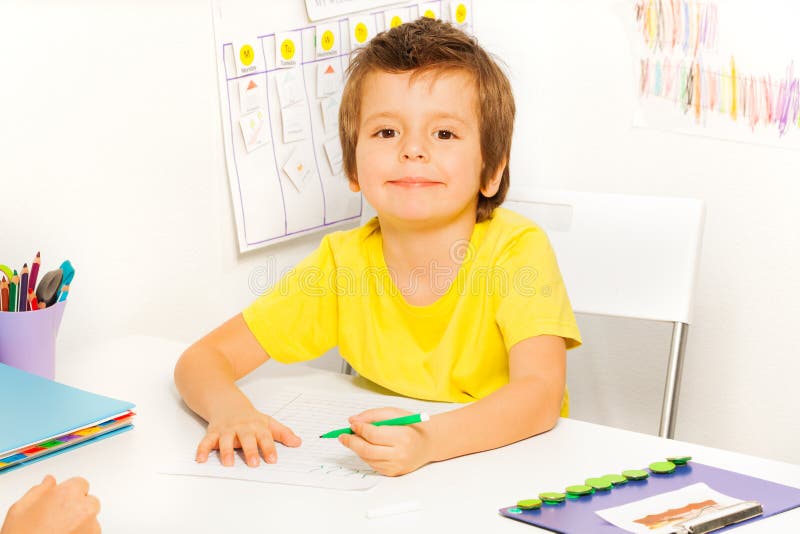 Boy draws with pen during sitting at table stock photography