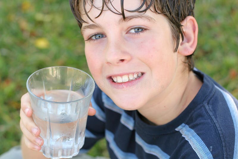 Ragazzo di bere un bicchiere di acqua sorriso.