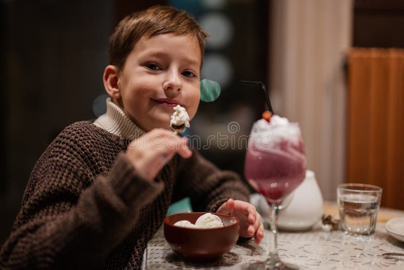 Boy Eating Dessert Ice Cream at Cozy Cafe and Having Fun Stock Photo
