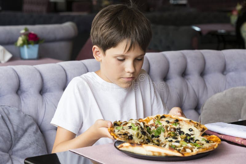 The boy is eating pizza stock image. Image of piece, food 99950367