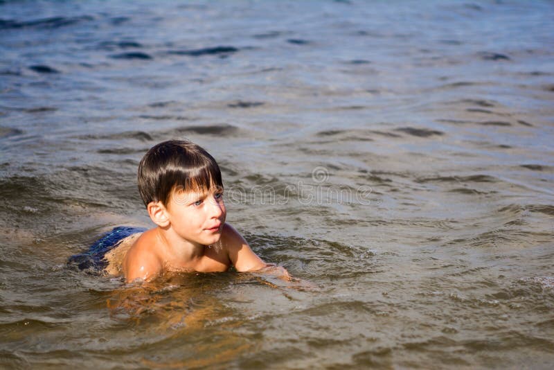 Boy enjoys swimming in the river.