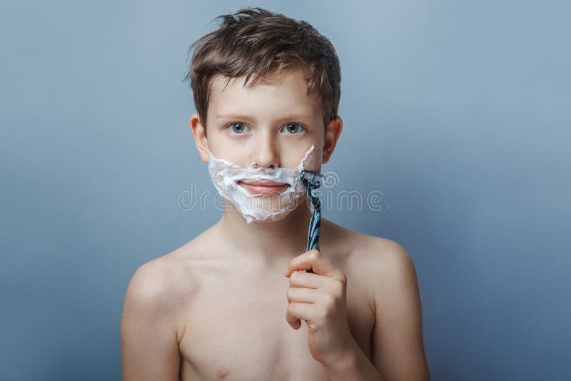 The boy of the European appearance decade person shaves, shaving foam on a gray background