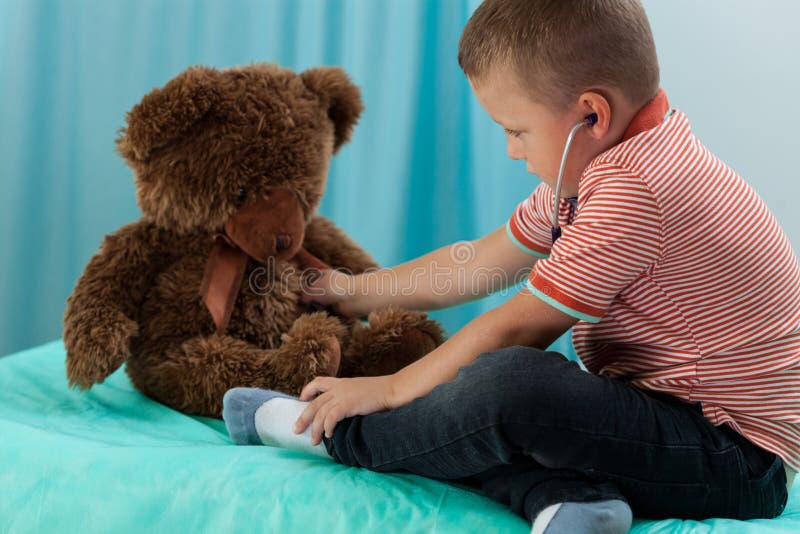 Boy examining teddy bear by stethoscope