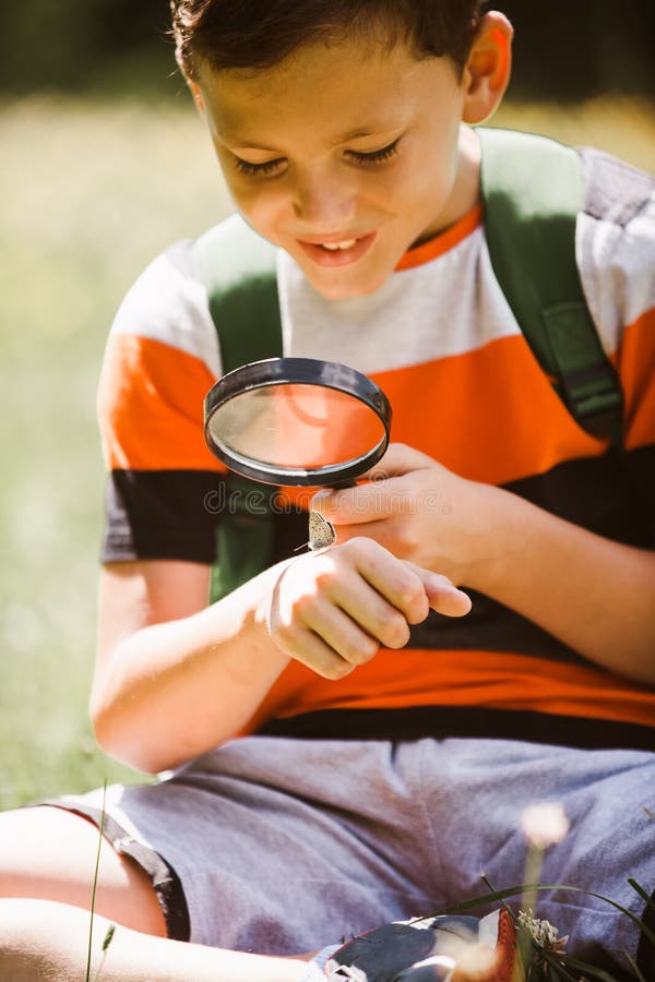 Boy exploring nature in a meadow with a magnifying glass royalty free stock photography