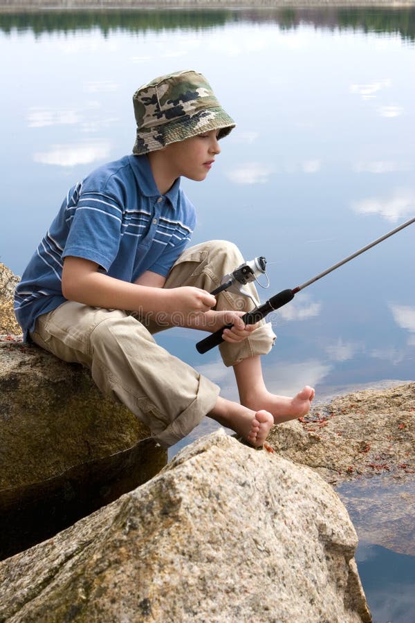 Bosý chlapec rybolovu na rybníku.