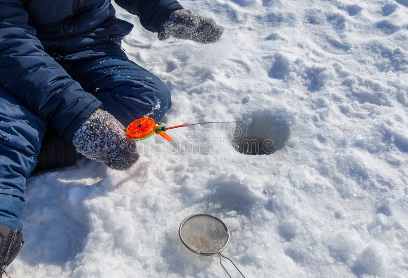 Boy fishing with a fishing rod on the ice in winter royalty free stock photos