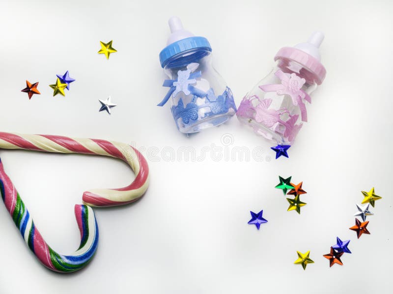 Is it a boy or a girl concept. Baby toy bottles for a boy and a girl. Twins baby shower. Baby announcement. Decoration with colorful stars, sweet candy cane heart shaped. Flat lay, copy space