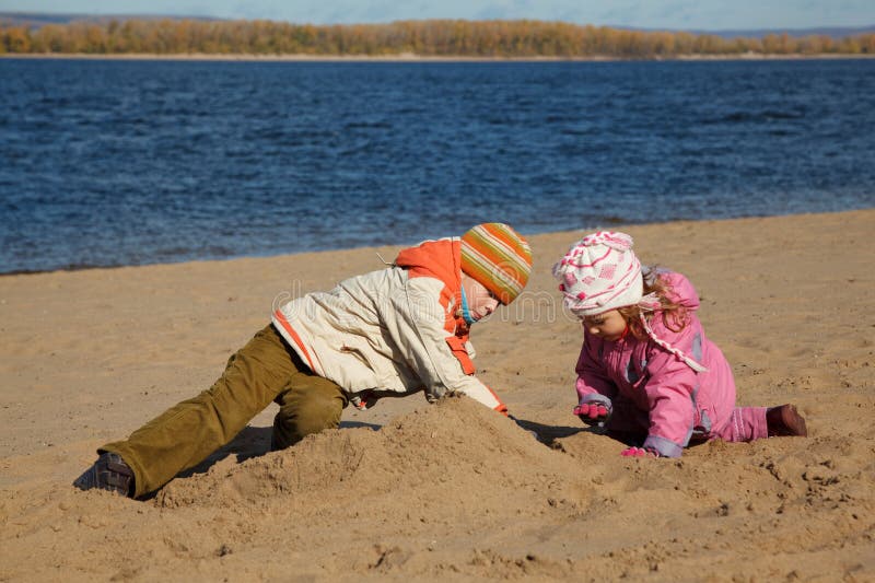 Boy and girl play sand on beach on river bank