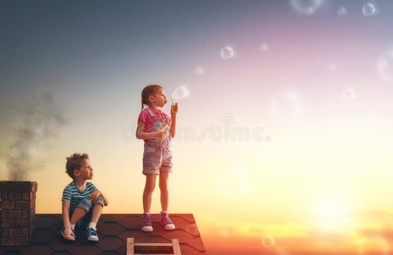 Băiat și fată care se joacă pe acoperiș stock photography