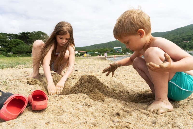 Boy and girl are playing with sand on the beach.