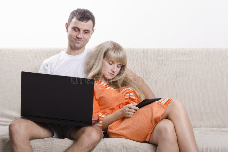 A boy and a girl sitting on the couch with the laptop and tablet royalty fr...